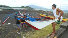 Warga dan nelayan membawa perahu kayu ke tempat yang lebih aman di sebuah desa di Kota Legaspi, provinsi Albay, selatan Manila, Filipina pada 16 November 2024. (CHARISM SAYAT/AFP)