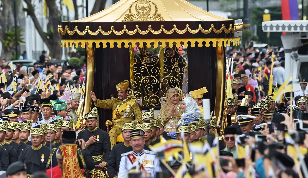 Sultan Hassanal Bolkiah dan Ratu Saleha Brunei saat naik kereta kerajaan melambaikan tangan kepada warga sekitar selama prosesi Golden Jubilee di Bandar Seri Begawan (5/10). Perayaan tersebut menandai 50 tahun bertahta. (AFP PHOTO / Roslan Rahman)