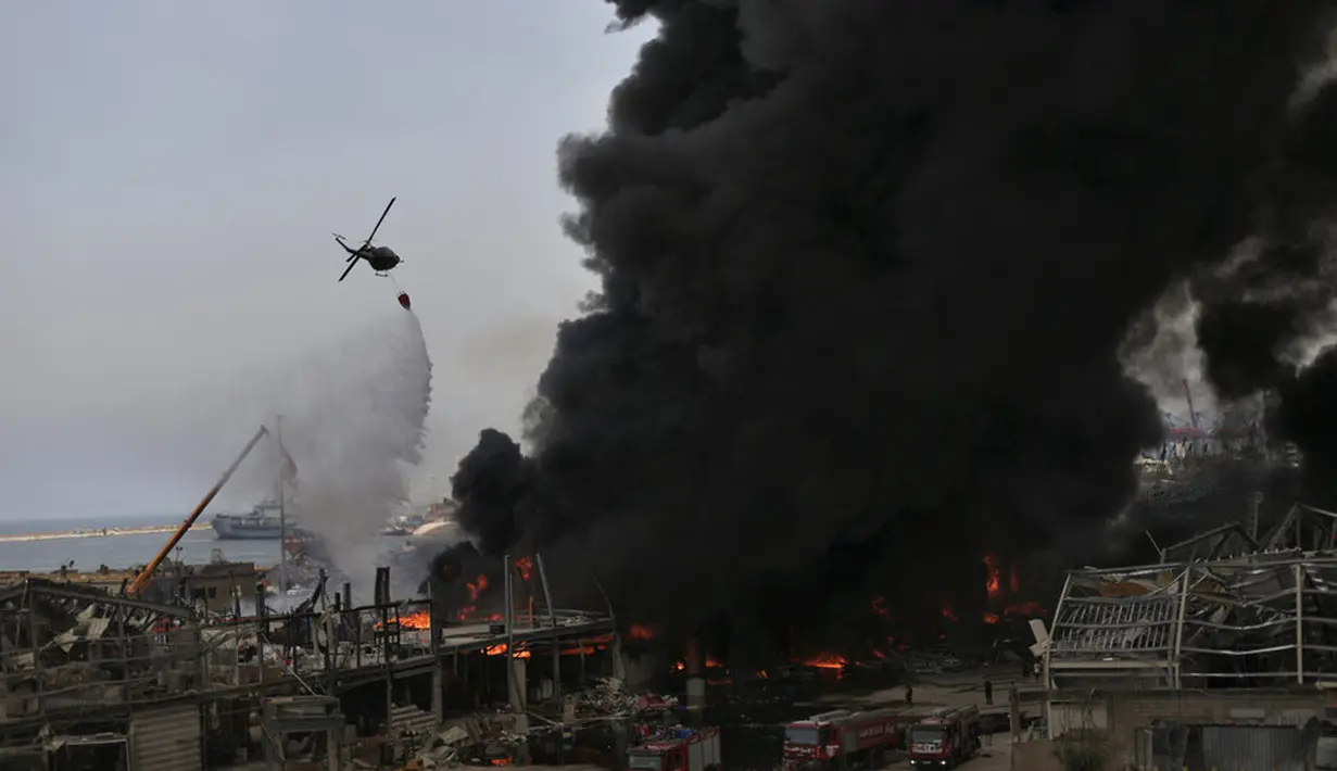 Helikopter tentara menjatuhkan air ke dalam api yang membakar gudang di Pelabuhan Beirut, Lebanon, Kamis (10/9/2020). Kebakaran tersebut menyebabkan kepanikan warga Beirut karena terjadi di lokasi ledakan dahsyat yang menewaskan 200 orang pada bulan lalu. (AP Photo/Hassan Ammar)