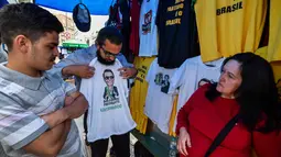 Pembeli memilih kaus bergambar Calon Presiden Brasil, Jair Bolsonaro dari sayap kanan dijajakan di sebuah toko pinggir jalan yang populer di Sao Paulo, 8 Oktober 2018. September lalu, Bolsonaro dirawat setelah ditusuk ketika kampanye. (AFP/NELSON ALMEIDA)