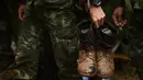 Tentara membawa sepatu yang berlumuran tanah saat mencari tim sepak bola remaja dan pelatih yang hilang  di Taman Hutan Non Khun Nam Nang dekat gua Than Luang di provinsi Chiang Rai, Thailand (28/6). (AFP Photo/Lillian Suwanrumpha)