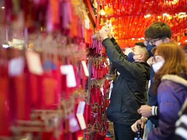 Seorang pria memasang kantong merah pada dinding Kuil Hongludi Nanshan Fude untuk menandai hari ketiga Tahun Baru Imlek di New Taipei City, Taiwan, Selasa (24/1/2023). (Sam Yeh/AFP)