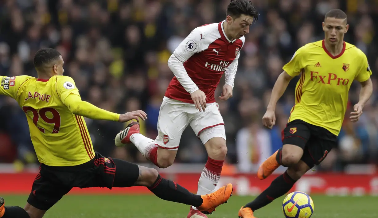 Gelandang Arsenal, Mesut Ozil, berusaha melewati pemain Watford pada laga Preimer League di Stadion Emirates, Minggu (11/3/2018). Arsenal menang 3-0 atas Watford. (AP/Matt Dunham)