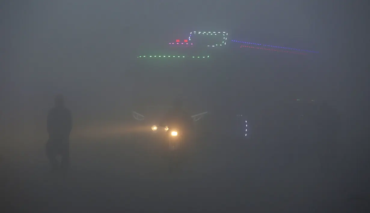 Bus dan pengendara sepeda motor melaju dengan menyalakan lampu depan saat kabut tebal menyelimuti Lahore, Pakistan, 15 Desember 2021. Kabut tebal membuat kendaraan harus melaju lambat karena jarak pandang berkurang. (AP Photo/K.M. Chaudary)