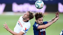 Bek Levante, Tono, duel udara dengan pemain Sevilla, Luuk De Jong, pada laga La Liga di Estadio Camilo Cano, Selasa (16/6/2020). Kedua tim bermain imbang 1-1. (AFP/Jose Jordan)