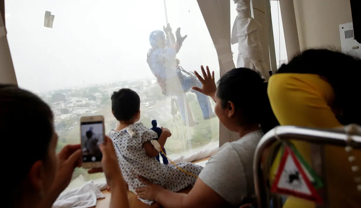 Petugas pembersih kaca berkostum Captain America mengejutkan pasien anak ketika turun dari atap rumah sakit anak-anak di Guadalupe, Meksiko, 30 April 2019. Mereka bergelantungan di luar jendela dengan mengenakan kostum superhero untuk menghibur anak- anak yang sedang sakit. (REUTERS/Daniel Becerril)
