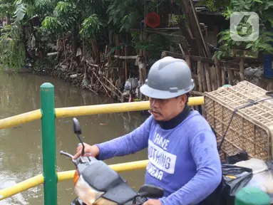 Warga melintas saat alat berat dioperasikan untuk pengerukan di Kali Mampang, Pondok Jaya, Sabtu (19/2/2022). Pengadilan Tata Usaha Negara (PTUN) Jakarta mengabulkan gugatan warga pada 19-21 Februari 2021 terkait program pencegahan banjir yang dilakukan Pemprov DKI. (Liputan6.com/Herman Zakharia)