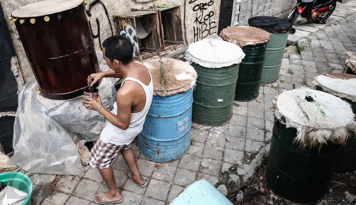 Ridho (52) mengecat tong dalam pembuatan bedug di kawasan Tanah Abang, Jakarta, Jumat (17/6). Menjelang lebaran, sejumlah pedagang menjual aneka ragam bedug yang dijual dari harga Rp.100 ribu hingga Rp. 4 juta. (Liputan6.com/Faizal Fanani)