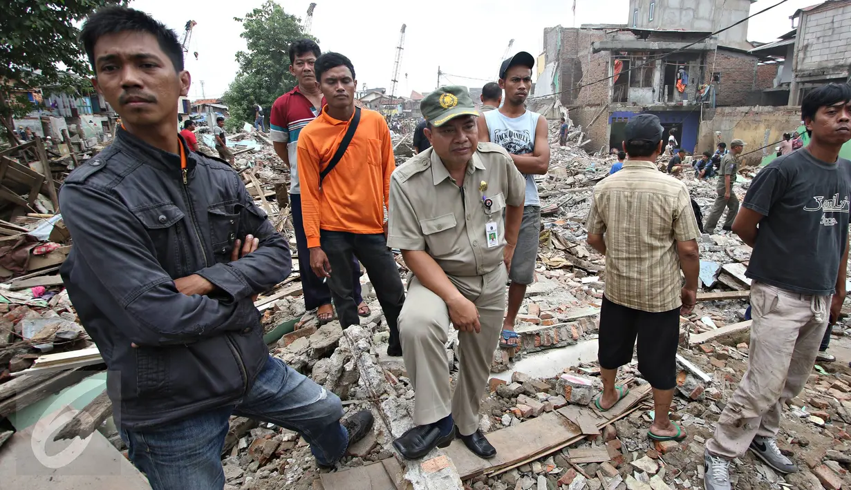 Warga berdiri di atas puing bangunan yang dibongkar di bantaran Sungai Ciliwung, Bukit Duri, Jakarta, Selasa (12/1). Pemprov DKI melakukan pembongkaran terhadap sejumlah bangunan terkait proyek normalisasi Sungai Ciliwung (Liputan6.com/ Immanuel Antonius)