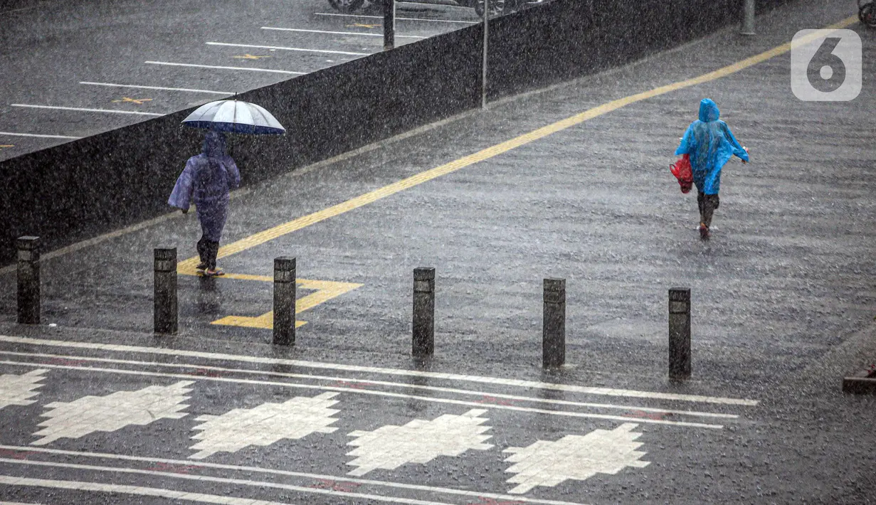 Warga berjalan saat turun hujan di Jalan Jenderal Sudirman, Jakarta, Minggu (18/10/2020). Badan Meteorologi, Klimatologi, dan Geofisika (BMKG) menyatakan musim hujan berlangsung mulai Oktober dan diprediksi mencapai puncaknya pada Januari hingga Februari 2021. (Liputan6.com/Faizal Fanani)