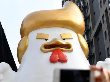 Patung ayam berukuran super besar dipajang di pusat perbelanjaan Tiongkok berhasil menyedot perhatian pengunjung, Sabtu (24/12). Pasalnya, patung ayam itu sangat mirip dengan presiden terpilih Amerika Serikat Donald Trump. (AFP PHOTO / STR)