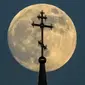 Bulan purnama di balik salib di atas sebuah gereja ortodoks di kota Rossosh di Voronezh, Rusia, pada Selasa 25 Mei 2021 (Kirill Kudryavtsev / AFP / Getty)