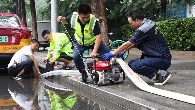 Para staf memompa genangan air di sebuah jalan di Distrik Haidian, Beijing, China (12/8/2020). Badan meteorologi Beijing memperkirakan hujan deras akan mengguyur wilayah Beijing-Tianjin-Hebei antara Rabu (12/8) hingga Kamis (13/8). (Xinhua/Ren Chao)