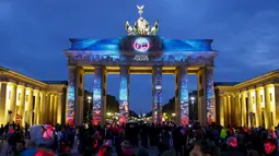 Wisatawan mengamati Gerbang Brandenburg yang dihiasi cahaya saat pembukaan Festival cahaya, Jerman, Sabtu (10/10/2015). Festival ini merupakan event tahunan yang diadakan setiap bulan Oktober selama dua belas hari.(REUTERS/Hannibal Hanschke)