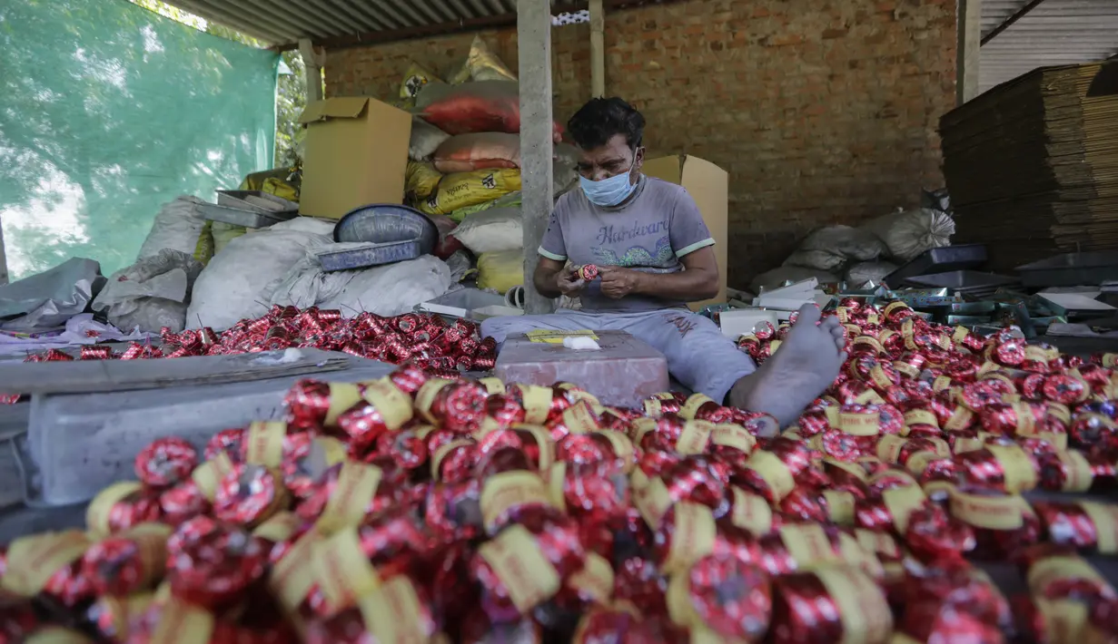 Pekerja mengenakan masker membuat petasan untuk festival Hindu Diwali mendatang di Ahmedabad, India, 28 Oktober 2020. Pihak berwenang sedang mempersiapkan diri menghadapi gelombang baru Covid-19, setelah festival keagamaan terpenting di negara itu, akan digelar pada 14 November. (AP/Ajit Solanki)