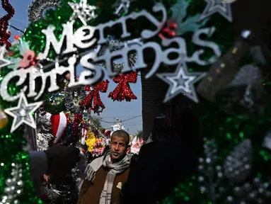 Seorang pria melintas di dekat barang-barang dekoratif yang dipajang di sebuah pasar menjelang perayaan Natal di New Delhi, India pada 13 Desember 2024. (Arun SANKAR/AFP)