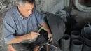 Pria Palestina Mohammed Al-Skafi mengolah sebuah ban kendaraan bekas untuk membuat keranjang penyimpanan di bengkel kerjanya di Kota Hebron, Tepi Barat (10/11/2020). Pria 68 tahun itu membuat dan menjual ember, ikat pinggang, dan keranjang penyimpanan dari ban bekas. (Xinhua/Mamoun Wazwaz)