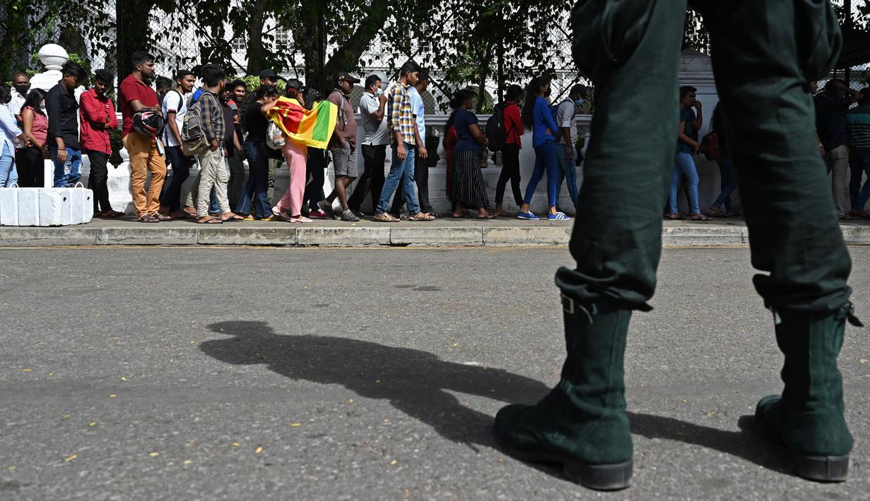 Orang-orang menunggu dalam antrean untuk mengunjungi kediaman resmi presiden Sri Lanka, beberapa hari setelah diserbu oleh pengunjuk rasa anti-pemerintah di Kolombo, Rabu (13/7/2022). Presiden Gotabaya Rajapaksa dilaporkan telah meninggalkan Sri Lanka dengan jet militer pada Rabu ini, di tengah protes massal atas krisis ekonominya. (Arun SANKAR / AFP)