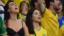 Dua fans wanita bersorak menunggu pertandingan antara Brasil melawan Argentina pada semifinal Copa America 2019 di Stadion Mineirao, Belo Horizonte, Brasil (2/7/2019). Di pertandingan ini Brasil menang 2-0 atas Argentina berkat gol striker Gabriel Jesus dan Roberto Firmino. (AFP Photo/Luis Acosta)