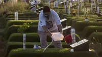 Seorang pria menyiramkan air ke makam kerabatnya di lokasi pemakaman korban virus corona COVID-19 di TPU Keputih, Surabaya, Jawa Timur, Sabtu (17/7/2021). Di Kota Surabaya terdapat dua tempat lahan pemakaman khusus blok COVID-19 yakni TPU Keputih dan TPU Babat Jerawat. (JUNI KRISWANTO/AFP)