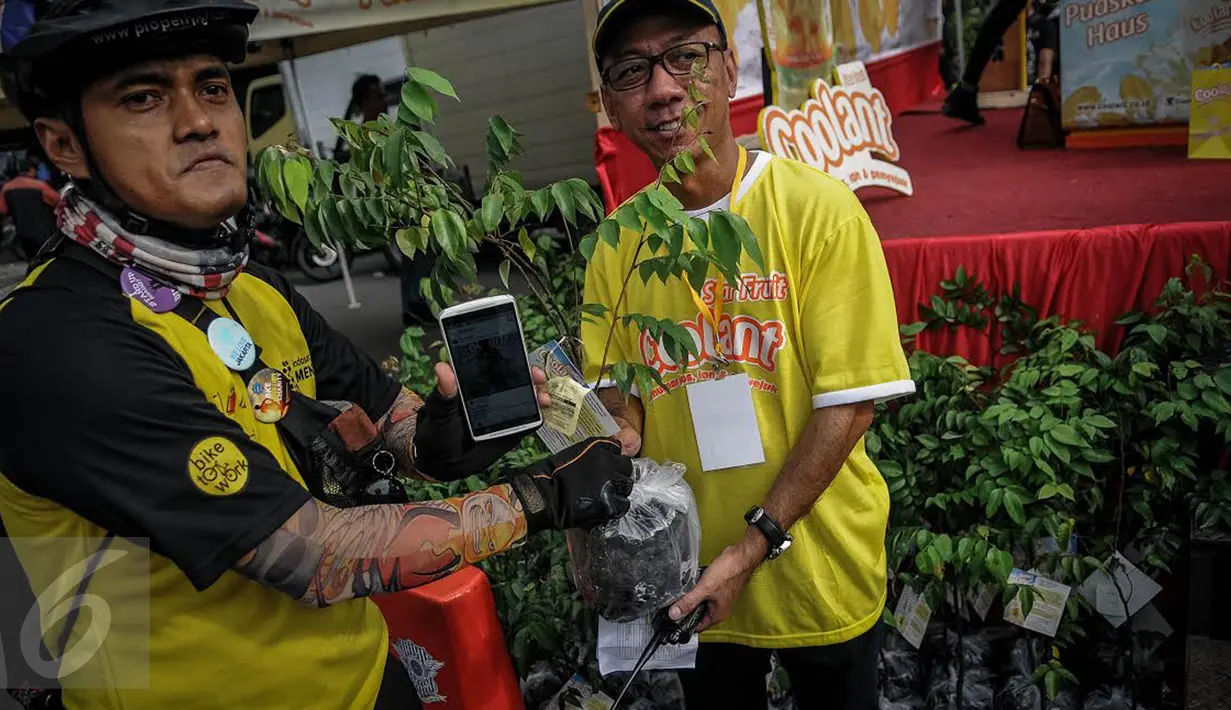 Warga mendapatkan bibit pohon belimbing disela kegiatan Coolant Star Fruit di arena Car Free Day, Jakarta, Minggu (25/9). Pembagian bibit itu untuk mengajak masyarakat melestarikan lingkungan dengan menanam tanaman produktif.  (Liputan6.com/Faizal Fanani)