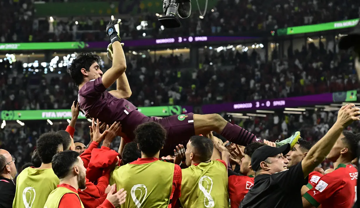 Para pemain Maroko melakukan selebrasi dengan melemparkan Yassine Bounou ke udara pada akhir pertandingan babak 16 besar Piala Dunia 2022 menghadapi Spanyol di Education City Stadium, Al Rayyan, Rabu (6/12/2022) dini hari WIB. Selain sujud syukur, para pemain Maroko juga berselebrasi dengan mengangkat dan melemparkan kiper asal Sevilla itu berulang kali ke atas. (JAVIER SORIANO / AFP)
