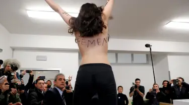 Seorang aktivis Femen melakukan aksi topless di tempat pemungutan suara di Milan, Italia, Minggu (4/3). Tempat itu lokasi di mana mantan PM Italia dan pemimpin partai Forza Italia Silvio Berlusconi akan memilih. (AP Photo/Antonio Calanni)