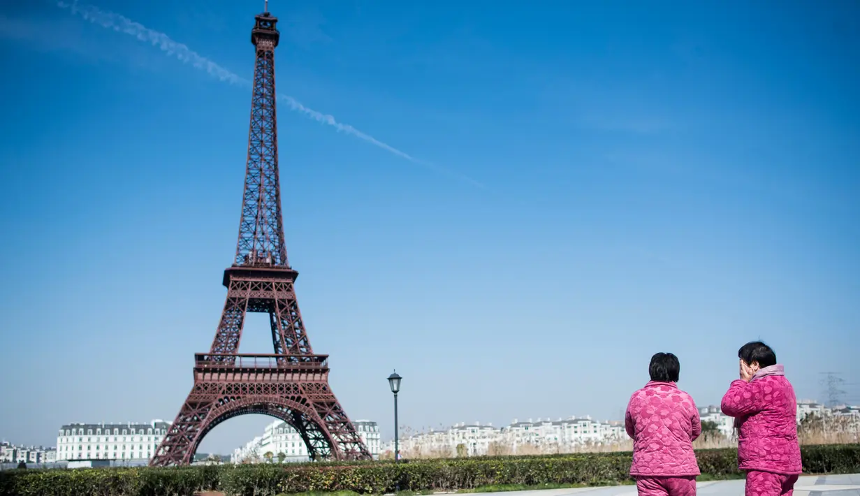 Dua wanita mengamati replika Menara Eiffel di Tianducheng, pinggiran Hangzhou, China, 26 Januari 2016. Kota Paris buatan yang didirikan di atas lahan seluas 19 km persegi ini membutuhkan waktu 5 tahun dalam pembangunannya. (AFP PHOTO/Johannes EISELE)