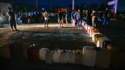Beberapa SPBU bahkan terpaksa menutup operasional karena tidak memiliki jenis BBM yang memadai untuk dijual kepada masyarakat. Tampak dalam foto, warga terdampak banjir mengantre untuk mendapatkan bahan bakar di sebuah Stasiun Pengisian Bahan Bakar Umum (SPBU) di Samahani, Provinsi Aceh, pada 2 Desember 2025. (CHAIDEER MAHYUDDIN/AFP)
