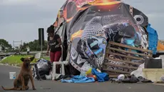 Seorang wanita yang kehilangan tempat tinggal akibat banjir berada di sekitar tenda darurat di jalan di lingkungan Humaita, Porto Alegre, negara bagian Rio Grande do Sul, Brasil, pada tanggal 8 Mei 2024. (Nelson ALMEIDA/AFP)