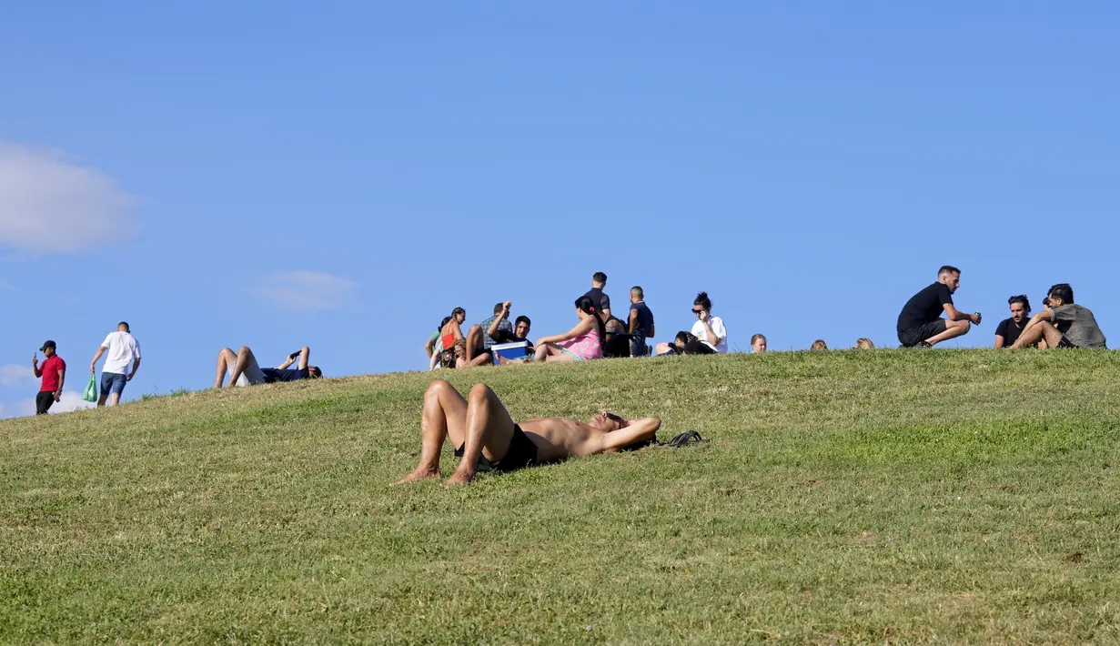 Orang-orang bersantai di sebuah taman di Madrid, Spanyol, Minggu (19/6/2022). Cuaca di Madrid dan sebagian besar Spanyol mulai mendingin pada Minggu setelah gelombang panas yang berlangsung sekitar seminggu. (AP Photo/Paul White)