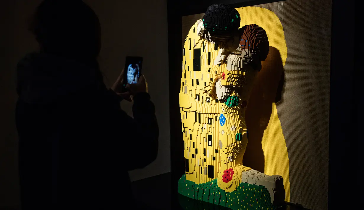 Seseorang mengambil gambar patung "Klimt kiss" yang terbuat dari susunan balok lego pada pameran Art of the Brick di Turin, Italia, Kamis (15/11). Pameran tersebut menampilkan berbagai patung lego karya seniman AS, Nathan Sawaya. (MARCO BERTORELLO/AFP)