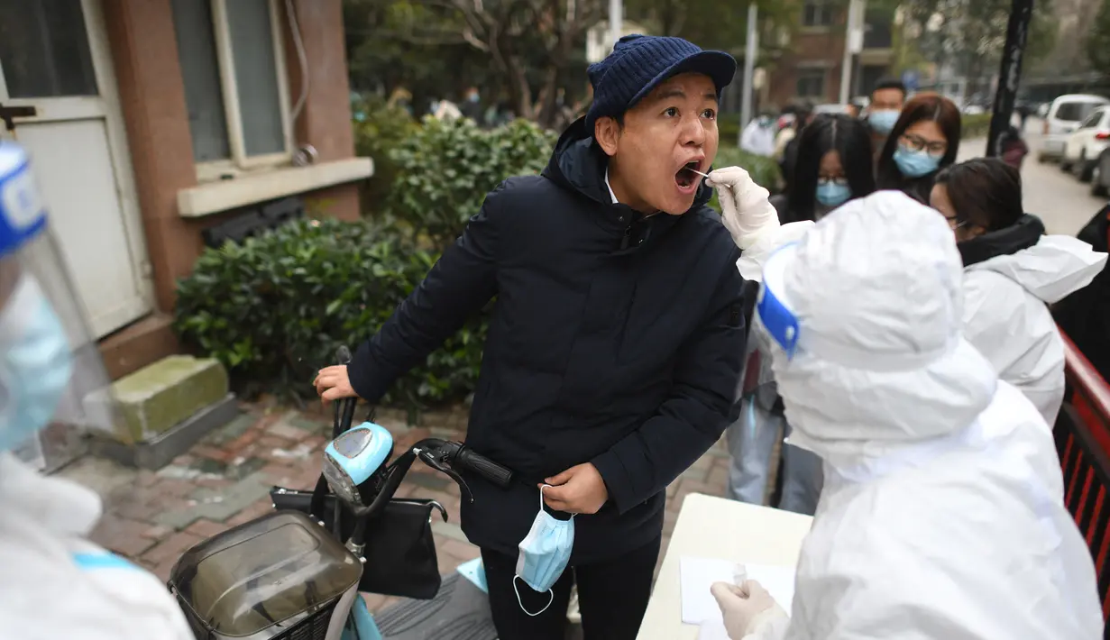 Seorang pria menjalani tes asam nukleat untuk virus corona Covid-19 di Wuhan di provinsi Hubei China tengah, Selasa (22/2/2022). Wuhan, wabah besar pertama dari pandemi virus corona melaporkan lebih dari selusin kasus virus corona baru minggu ini. (AFP/STR)