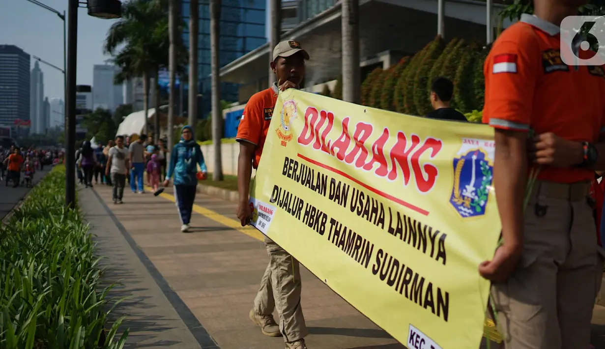 Spanduk larangan berjualan yang dibentangkan petugas Satpol PP di jalur Hari Bebas Kendaraan Bermotor atau Car Free Day, Jakarta, Minggu (3/11/2019). Pemprov DKI melarang PKL berjualan di sepanjang jalur Car Free Day yang selama ini memenuhi jalan serta trotoar. (Liputan6.com/Immanuel Antonius)
