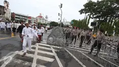 Massa aksi 31 Maret melintasi petugas polisi yang sedang memasang kawat berduri di sekitar Istana Negara, Jakarta, Jumat (31/3). Kawat berduri tersebut dipasang untuk mengantisipasi ricuh aksi 31 Maret. (Liputan6.com/Immanuel Antonius)