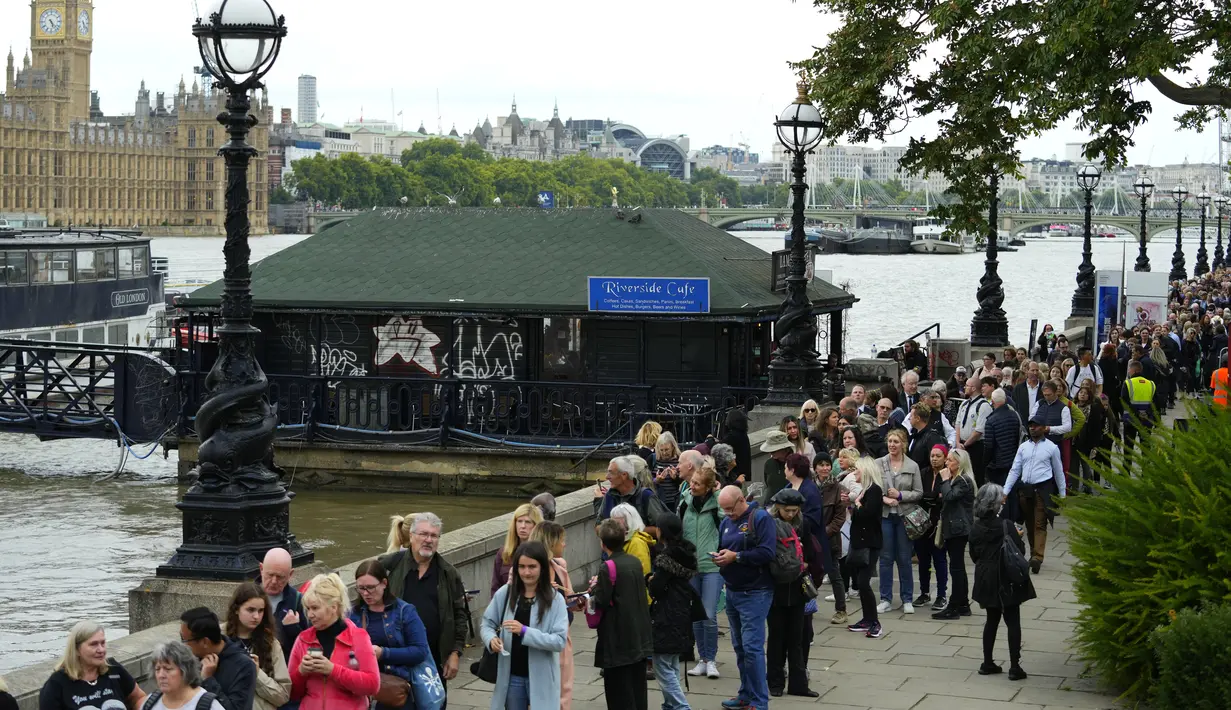 Orang-orang berjalan melewati Riverside Cafe saat mengantre untuk memberi penghormatan kepada mendiang Ratu Elizabeth II di Westminster Hall, London pada 15 September 2022. Hotel, restoran, dan toko-toko penuh sesak saat penggemar kerajaan berdatangan ke jantung kota London untuk melihat jalan-jalan yang dipagari bendera, prosesi yang dipenuhi kemegahan, dan berani mengantre sejauh bermil-mil untuk mengucapkan selamat tinggal kepada Ratu Elizabeth II. (AP Photo/Petr David Josek, File)