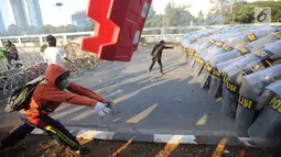 Massa aksi melemparkan benda ke arah polisi yang membentuk barikade dengan tameng di dekat Gedung DPR/MPR, Jalan Gatot Subroto, Jakarta, Senin (30/9/2019). Aksi unjuk rasa dari berbagai elemen itu menyikapi penolakan terhadap UU KPK dan sejumlah RUU yang dinilai bermasalah. (merdeka.com/Arie Basuki)