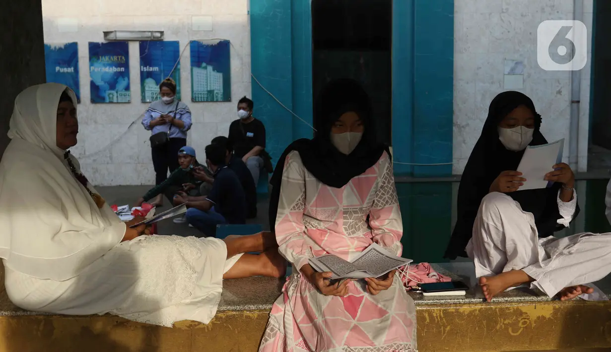 Umat Islam membaca Al-Quran sambil menunggu waktu berbuka puasa di halaman Masjid Raya Jakarta Islamic Center, Jakarta Utara, Senin (18/4/2022). Acara ngabuburit sambil khataman Al-Quran ini merupakan rangkaian acara menyambut 17 Ramadhan atau malam Nuzulul Quran. (Liputan6.com/Herman Zakharia)