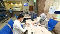 Nasabah Unit Usaha Syariah (UUS) PT Bank Tabungan Negara (Persero) Tbk. tengah melakukan transaksi di kantor BTN Syariah di Jakarta, Rabu (06/04/2021). BTN Syariah tetap mencatatkan pertumbuhan kinerja mencapai double digit kendati berada di masa pandemi. (Liputan6.com/Pool/BTN)