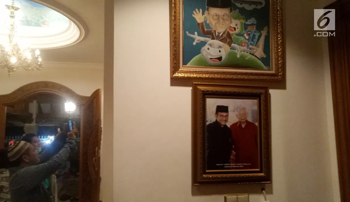 Pelayat memotret koleksi foto dan lukisan di rumah duka Presiden ke-3 RI BJ Habibie, Patra Kuningan, Jakarta, Rabu (11/9/2019). BJ Habibie menghembuskan napas terakhirnya pada usia 83 tahun. (Liputan6.com/Angga Yuniar)