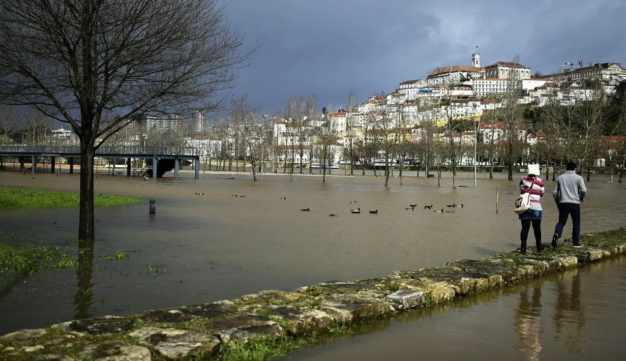 Pasangan muda mudi sedang berjalan diantara genangan air di taman Coimbra, Portugal (14/2/2016). Tak hanya menyebabkan banjir, cuaca buruk juga menyebabkan tanah longsor di bagian lain negara Portugal. (AFP Photo /Francisco Leong)
