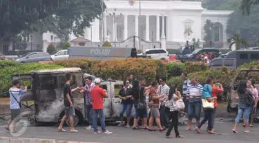 Sejumlah warga melihat mobil aparat yang dibakar demonstran 4 November di kawasan Monas, Jakarta, Sabtu (5/11). Pengunjung menjadikan dua kendaraan milik kepolisian tersebut sebagai objek foto dan melakukan swafoto. (Liputan6.com/Angga Yuniar)