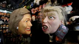 Seorang karyawan memegang topeng yang menggambarkan calon presiden Demokrat Hillary Clinton dan calon presiden dari partai Republik Donald Trump untuk menyambut Hallowen disebuah toko mainan di Los Angeles, California, AS (26/10). (Reuters/Mario Anzuoni)