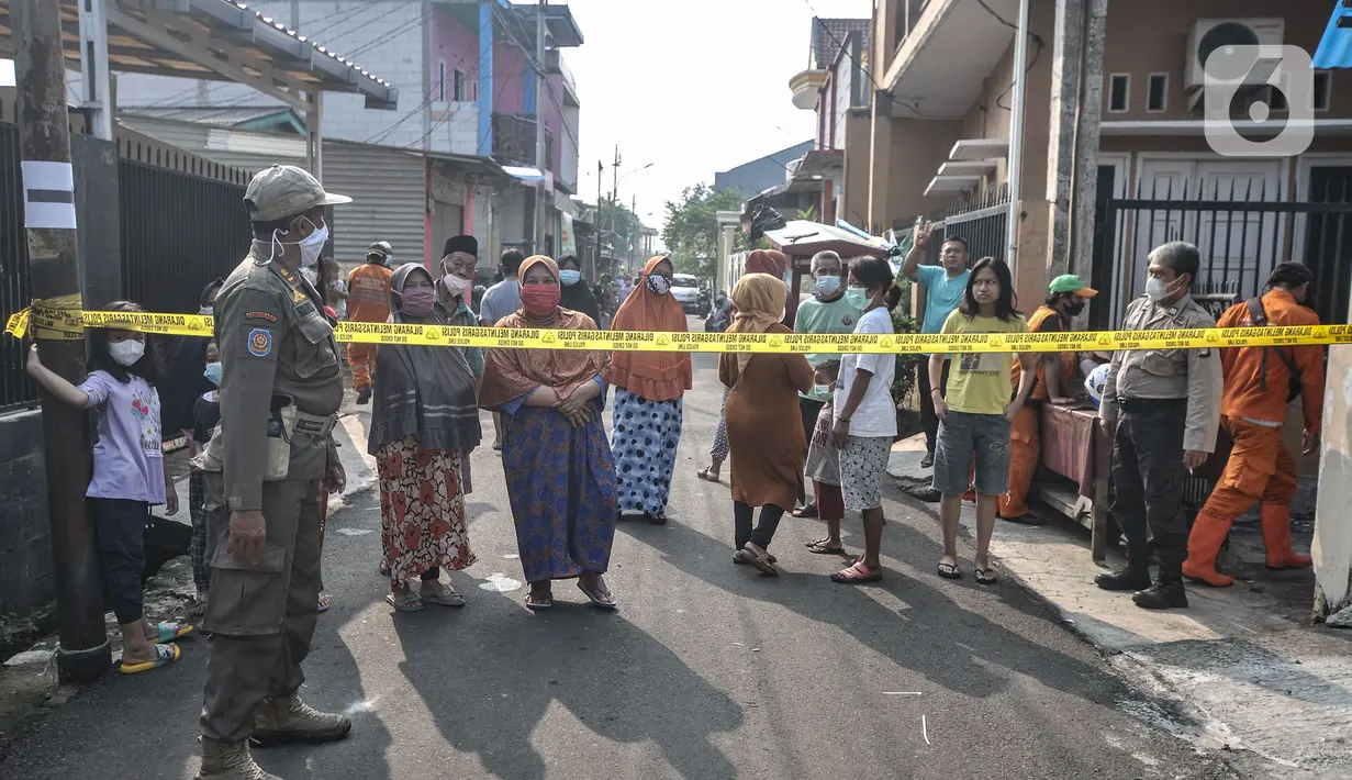 Warga menyaksikan proses pembongkaran makam dari kejauhan di Buaran, Jakarta Timur, Senin (24/5/2021). Jenazah Trio yang meninggal pada (17/5) lalu atau sehari setelah disuntik vaksin AstraZeneca akan menjalani autopsi di RSCM guna memastikan penyebab kematiannya. (merdeka.com/Iqbal S. Nugroho)