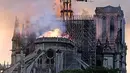 Api dan asap mengepul dari puncak menara Gereja Katedral Notre-Dame dalam kebakaran di pusat kota Paris, Prancis, pada Senin (15/4). Hingga kini belum diketahui pasti apa yang menjadi penyebab utama terbakarnya salah satu situs warisan dunia UNESCO tersebut. (AP Photo/Diana Ayanna)