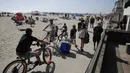 Pengunjung menggunakan jalur sepeda dan berjalan di Pantai Newport selama masa pandemi covid-19 di California pada Minggu (24/5/2020). Warga Amerika Serikat memilih berjemur di pantai ketika angka kematian akibat virus corona di negara itu mendekati 100.000 orang. (AP/Marcio Jose Sanchez)