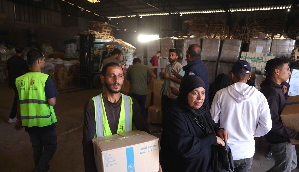 Warga Palestina tiba di pusat distribusi untuk mengambil kotak ransum makanan yang disediakan oleh Program Pangan Dunia (WFP) di desa Al-Zawayda, di tengah-tengah Jalur Gaza pada 27 Oktober 2025. (BASHAR TALEB/AFP)