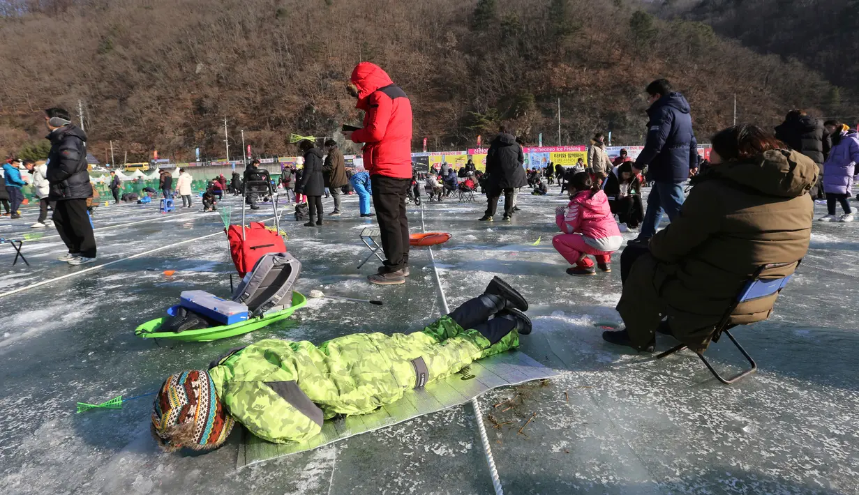 Peserta memancing ikan trout melalui lubang yang mereka buat di atas sungai beku di Hwacheon, Korea Selatan, Sabtu (5/1). Kontes ini merupakan bagian dari festival es tahunan yang menarik lebih dari satu juta pengunjung setiap tahun. (AP/Ahn Young-joon)