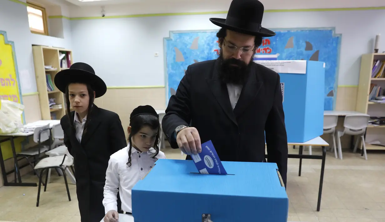 Anak-anak menyaksikan pria Yahudi ultra-Ortodoks memberikan suaranya selama pemilihan parlemen Israel di Yerusalem (9/4). Warga Israel hari ini memberikan suara dalam pemilihan tingkat tinggi yang akan memutuskan masa jabatan PM Benjamin Netanyahu. (AFP Photo/Menahem Kahana)