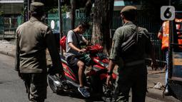 Petugas menghentikan pengendara motor saat Razia Protokol Kesehatan di kawasan Kebayoran Lama, Jakarta, Selasa (19/10/2021). Razia PPKM Level 3 kerap dilakukan demi memutus rantai penyebaran covid 19, dengan sanksi denda Rp 100.000 dan sanksi sosial seperti menyapu jalan. (Liputan6.com/Johan Tallo)